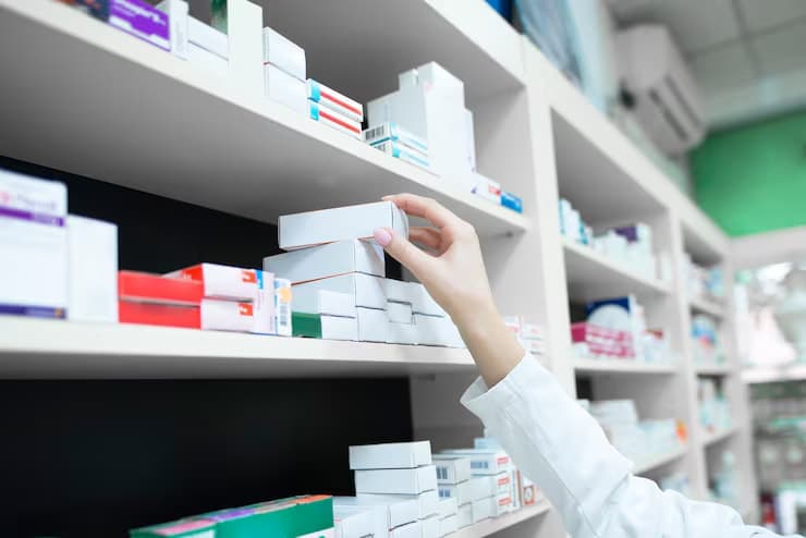 Pharmacist taking medicine boxes from a pharmacy shelf